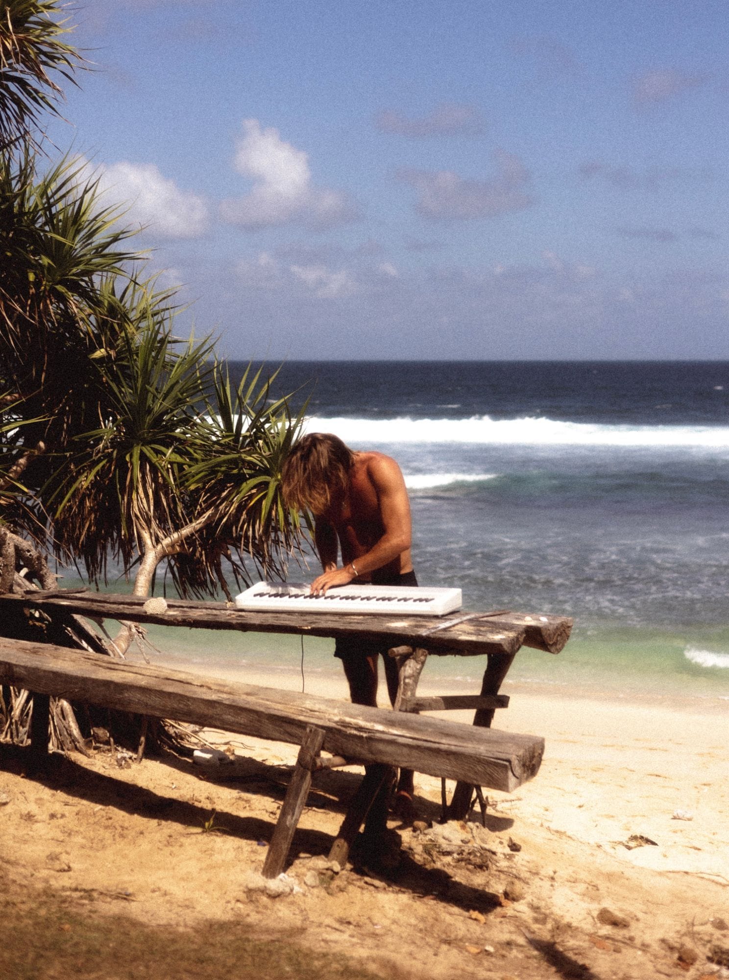 Pianofrenchy playing a white keyboard on a wooden table by the ocean
